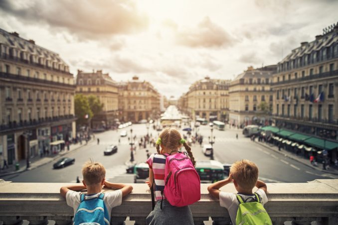 Three kids visiting Paris. They are looking from the balcony of Paris Opera at the place de l'opera. The girls is aged 9 and her brothers are aged 6.